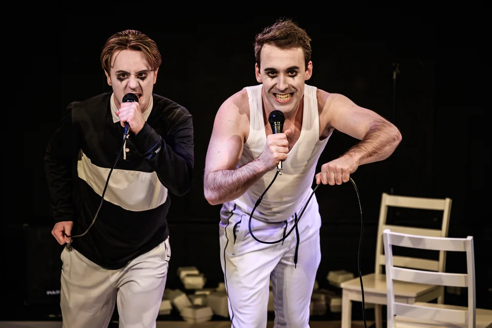 Nick Hyde and Oliver Maynard leaning towards the audience with microphones