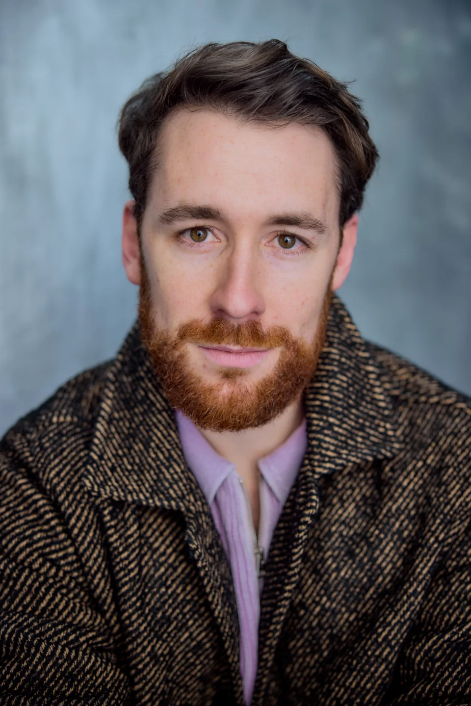 Headshot in a lilac shirt and dark coat
